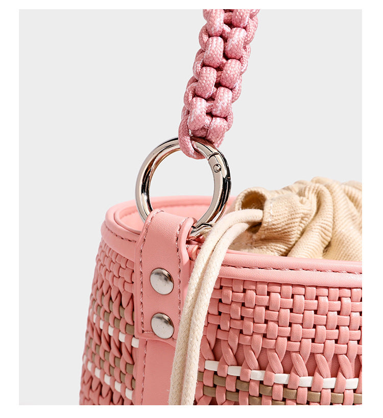 Detailansicht einer zylindrischen, handgeflochtenen Beuteltasche mit geflochtenem Henkel, Kordelzugverschluss, Kordelquasten und Metallringbeschlägen