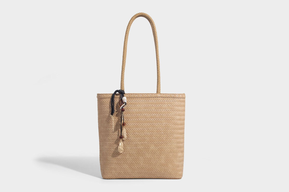 Structured woven herringbone tote bag with braided double shoulder handles in tan brown, shown with matching drawstring