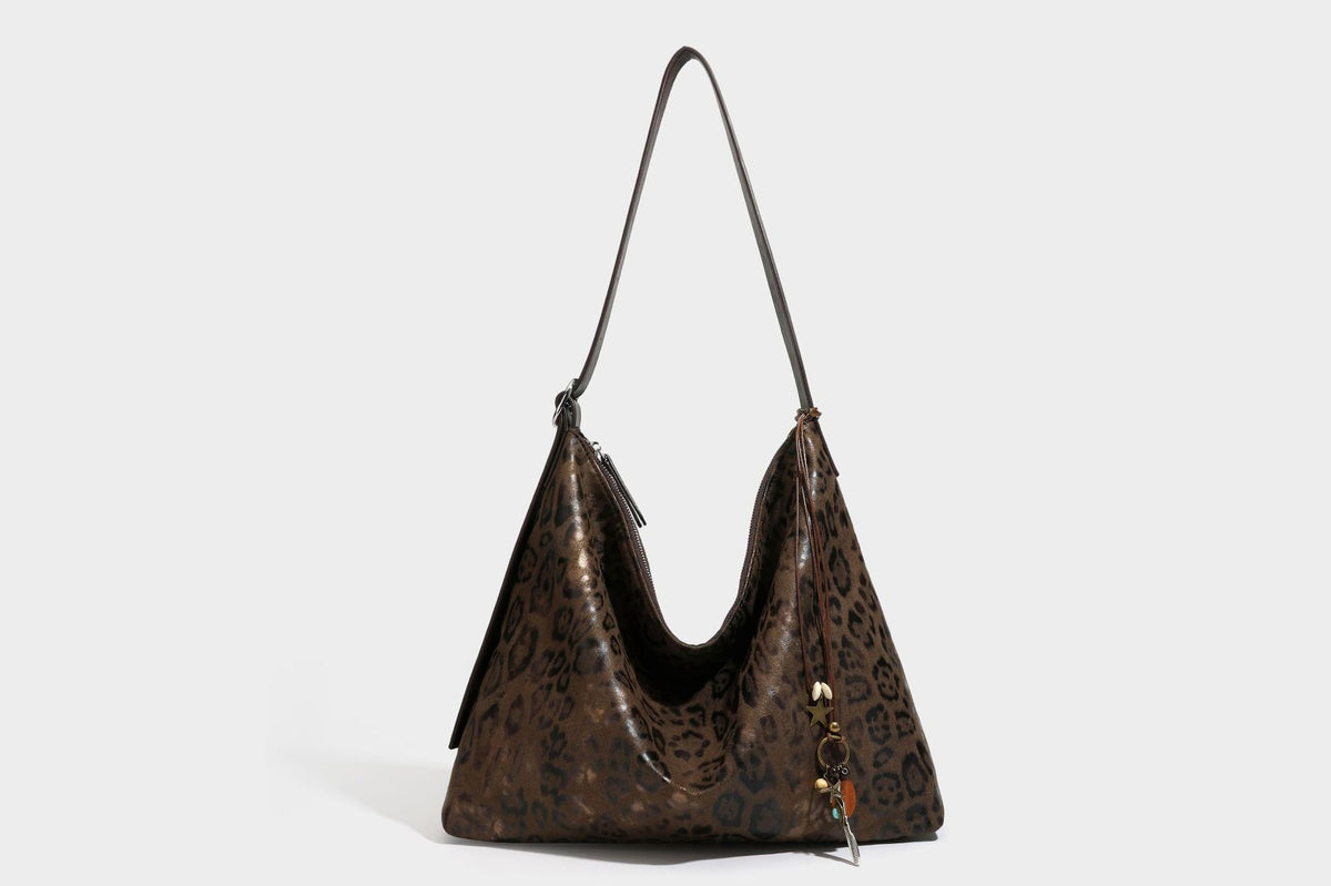 Slouchy leopard print hobo shoulder bag with glossy coated finish, top zipper closure, dark brown trim, and dangling charm