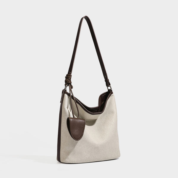Cremefarbene Canvas-Beuteltasche mit dunkelbraunem Besatz in Lederoptik, geknotetem Riemen und befestigter Mini-Tasche, Detailansicht 2