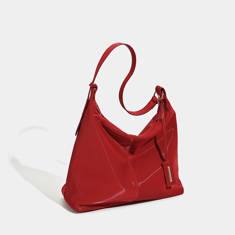 Large red glossy leather-look slouchy hobo shoulder tote bag with zip-top closure and gold-tone hardware, detail view 2