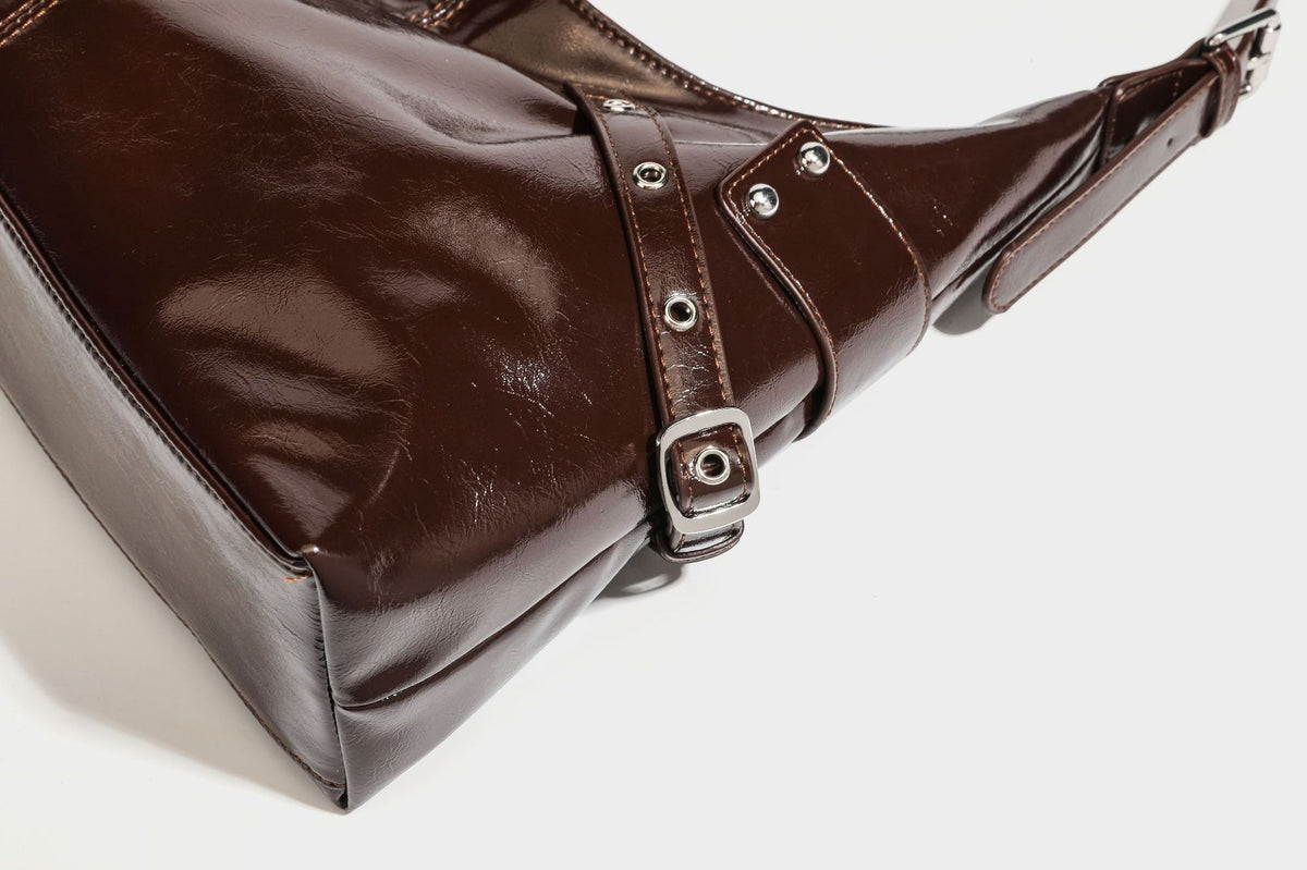 Glänzende dunkelbraune, lässig geschnittene Hobo-Schultertasche mit Riemendetail mit silberfarbenen Ösen, Reißverschlussfach auf der Vorderseite und Herz mit Leopardenmuster
