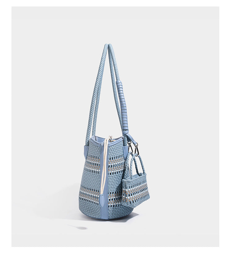 Light blue open-weave woven bucket tote bag with long braided shoulder straps, drawstring side ties, and attached mini pouch