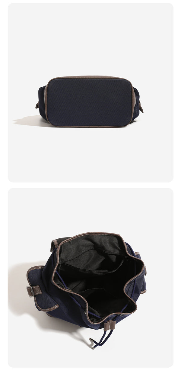Deep navy canvas backpack with brown textured leather-look trim, drawstring flap closure, buckle-strap front detail, and