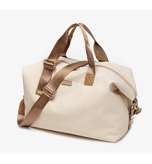 Structured woven duffel bag with dual tan webbing handles, detachable shoulder strap, top zip closure, and gold-tone