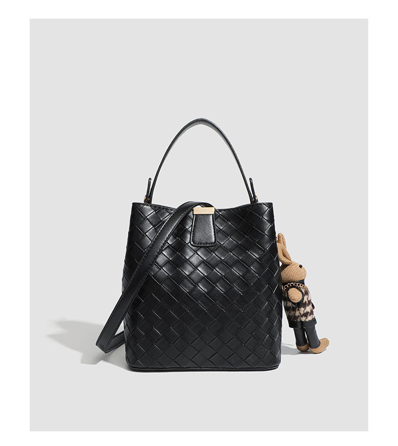 Black woven leather-look bucket bag with gold-tone clip closure, top handle, detachable shoulder strap, and knit bunny charm
