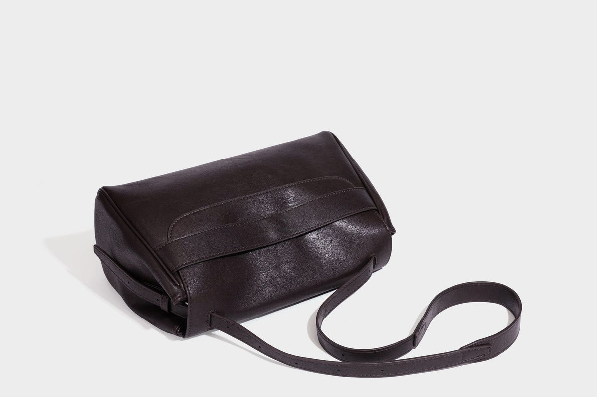 Formstabile rechteckige Schultertasche in Dunkelbraun mit Lederoptik, Überschlag und mehrlagigem Frontdetail sowie langem verstellbarem Riemen, Detail