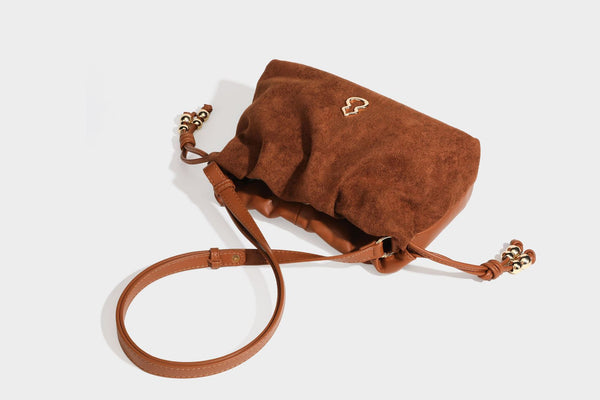 Suede-look drawstring shoulder bag in brown with smooth trim, knotted bead drawstring closure, slim adjustable strap, and