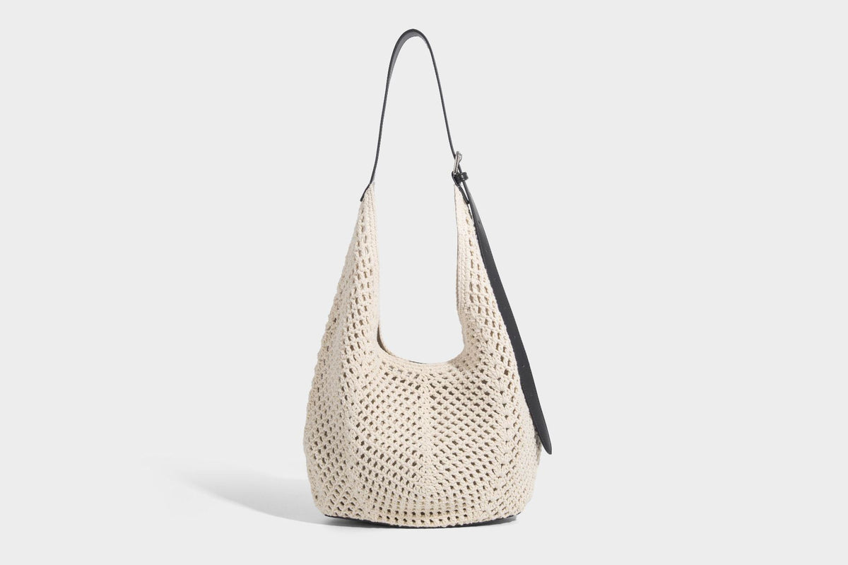 Cream openwork crochet hobo bag with black leather-look strap and trim patch accent, slouchy teardrop silhouette, detail view