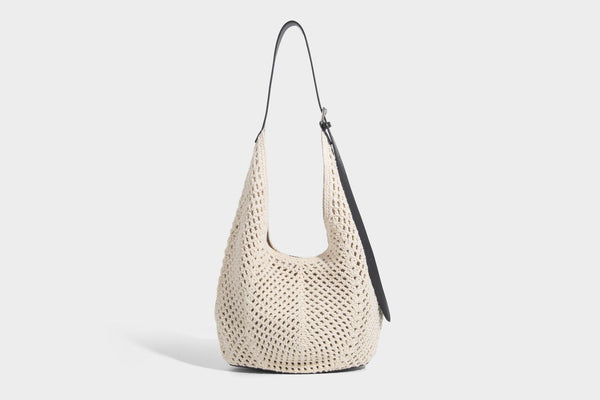 Cream openwork crochet hobo bag with black leather-look strap and trim patch accent, slouchy teardrop silhouette, detail view