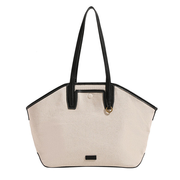Trapezförmige Tote-Bag aus cremefarbenem Canvas mit schwarzem Besatz in Lederoptik, zwei Schulterriemen und goldfarbenen Ringbeschlägen, Detailansicht