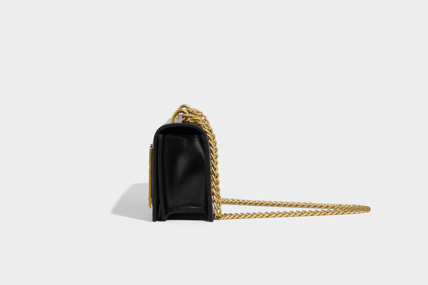 Structured rectangular crossbody bag with glossy finish, three vertical gold-tone embossed plaques, and gold chain strap