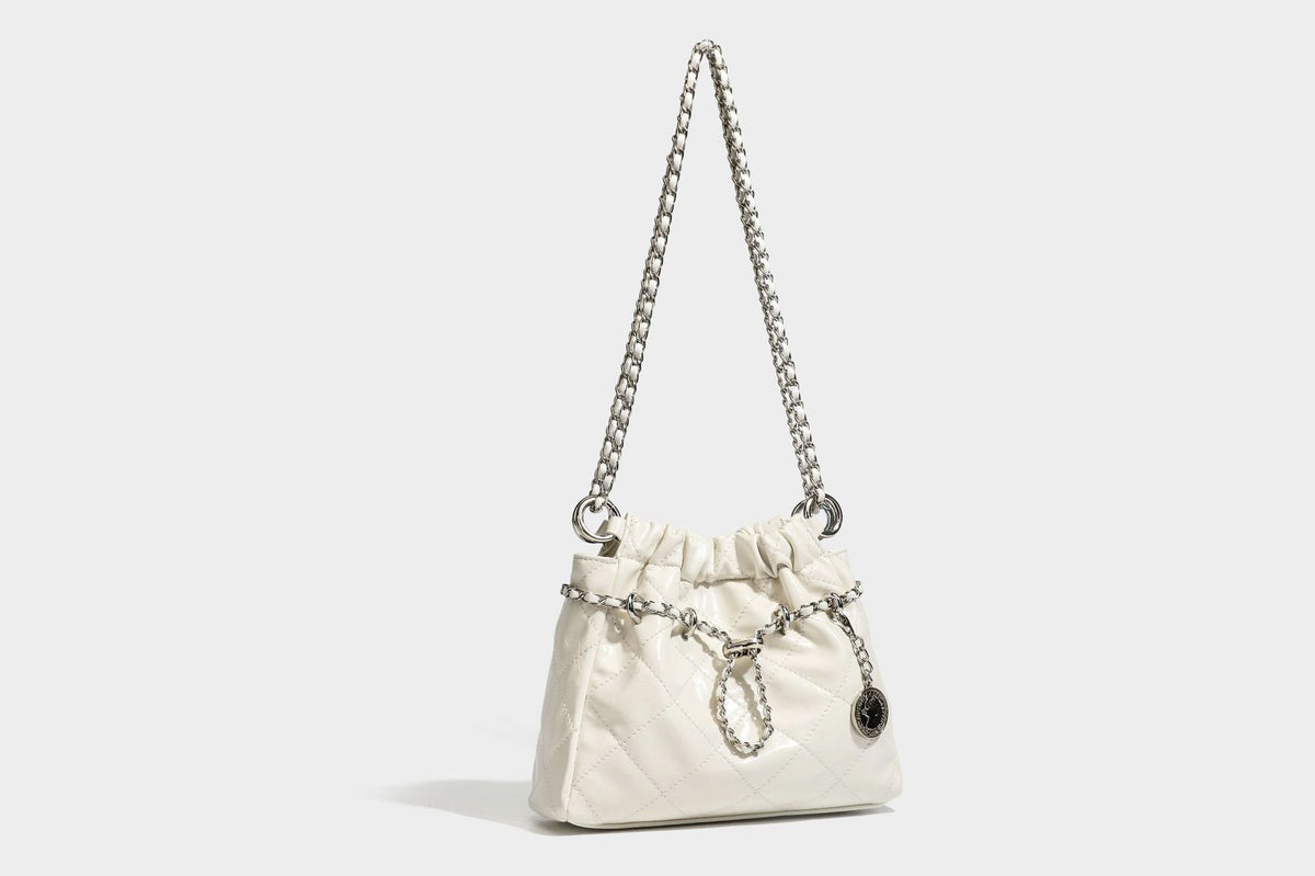Glossy diamond-quilted drawstring bucket bag with silver chain shoulder strap and medallion charm, detail view 23