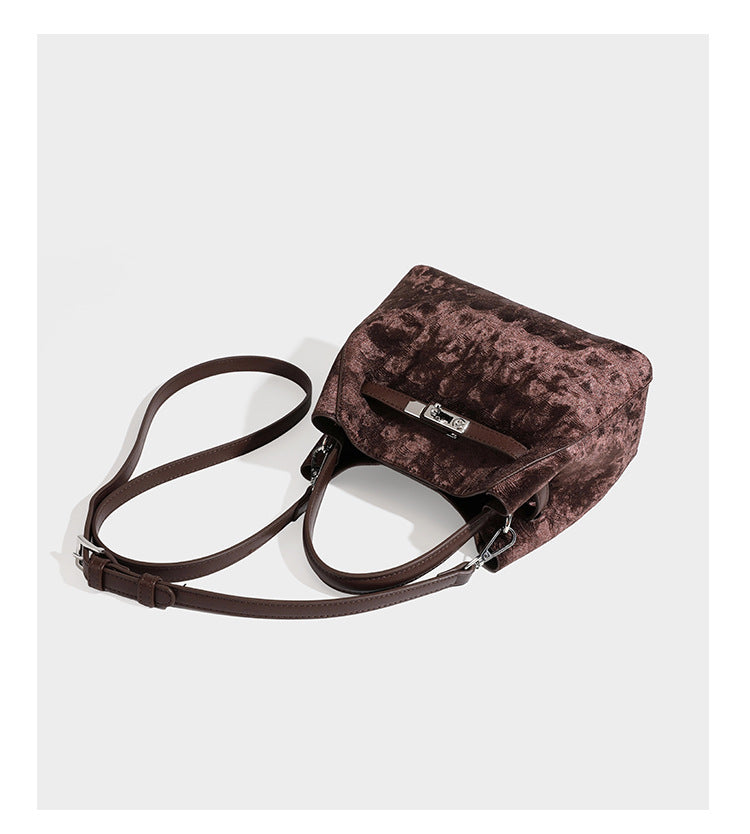 Small structured bucket satchel in embossed velvet-texture fabric with silver turn-lock hardware, rounded top handle, and