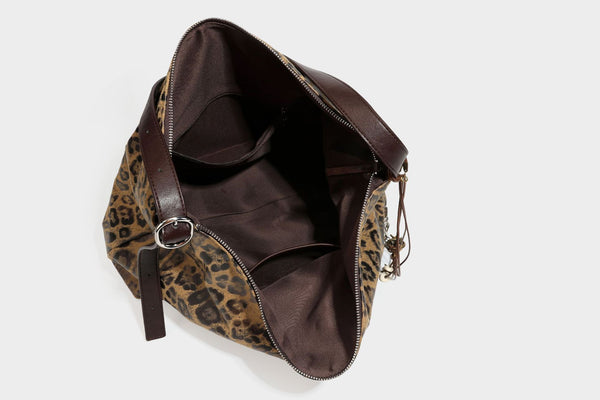 Slouchy leopard print hobo shoulder bag with glossy coated finish, top zipper closure, dark brown trim, and dangling charm