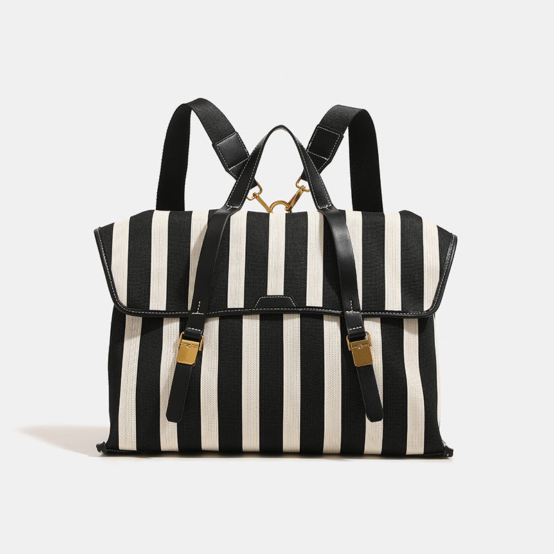 Structured striped canvas convertible satchel bag with leather-look trim, gold-tone buckle hardware, and backpack straps