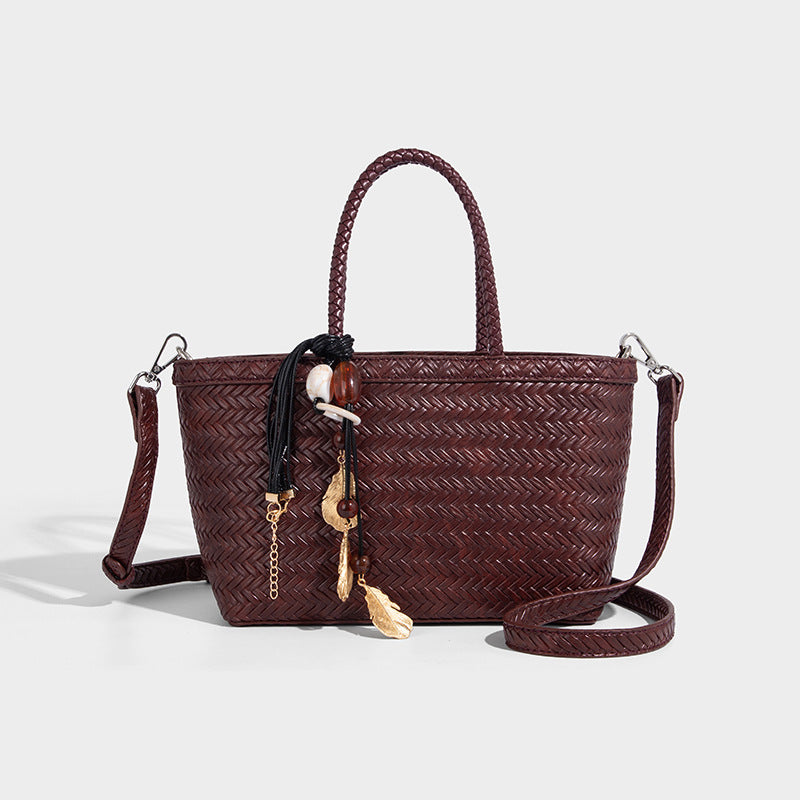 Structured chevron woven leather-look tote bag with braided top handles, gold feather charm, and adjustable shoulder strap