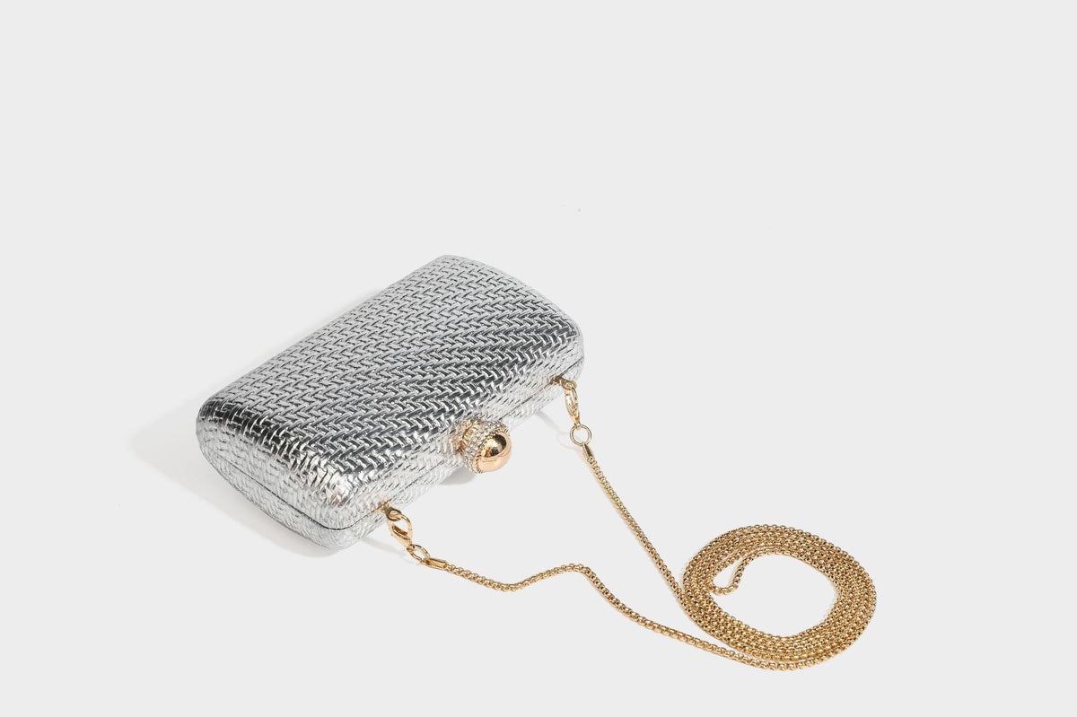 Small structured metallic woven-texture box clutch bag with jeweled kiss-lock dome clasp and slim gold chain strap, detail