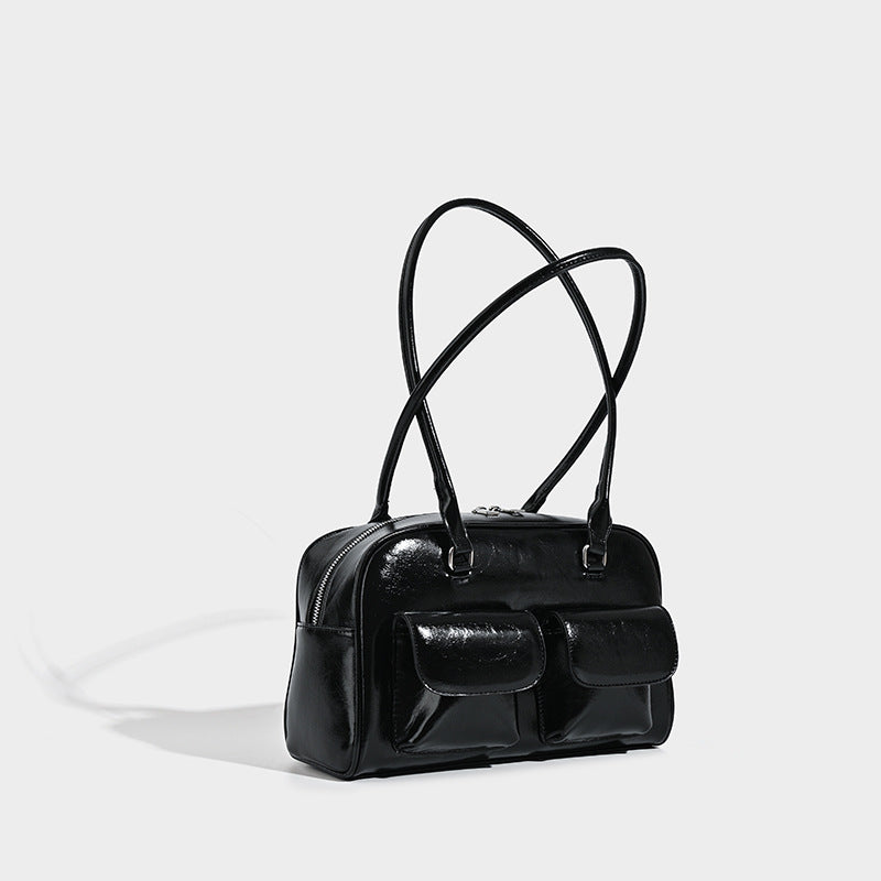 Structured glossy leather-look bowling bag with two front flap pockets, zip-top closure, and long twin shoulder straps
