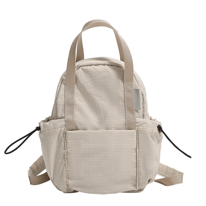 Mini rounded convertible backpack handbag in matte ripstop fabric with dual top handles, adjustable straps, and side, detail