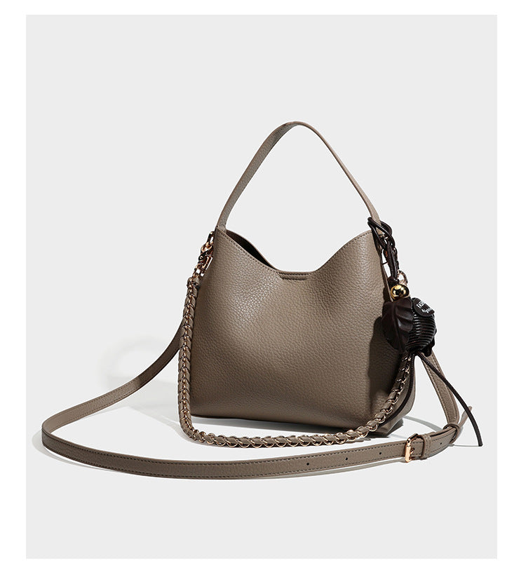Hobo-Schultertasche in genarbtem Lederlook mit goldfarbener Kette als Schulterriemen, kurzem Tragegriff und dekorativem seitlichem Anhänger, Detailansicht
