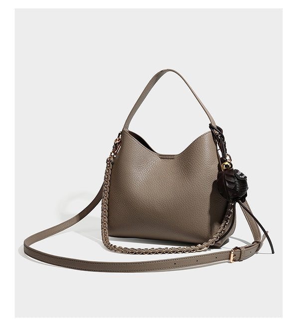 Hobo-Schultertasche in genarbtem Lederlook mit goldfarbener Kette als Schulterriemen, kurzem Tragegriff und dekorativem seitlichem Anhänger, Detailansicht