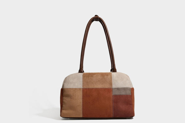 Boxy patchwork suede-look shoulder tote in tan, beige, rust, and brown panels with double brown straps and hanging doll