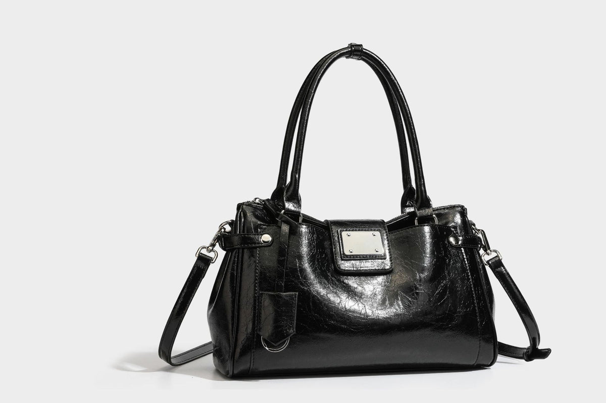 Structured glossy crinkled leather-look satchel with double top handles, front metal-plaque tab, silver-tone hardware, and