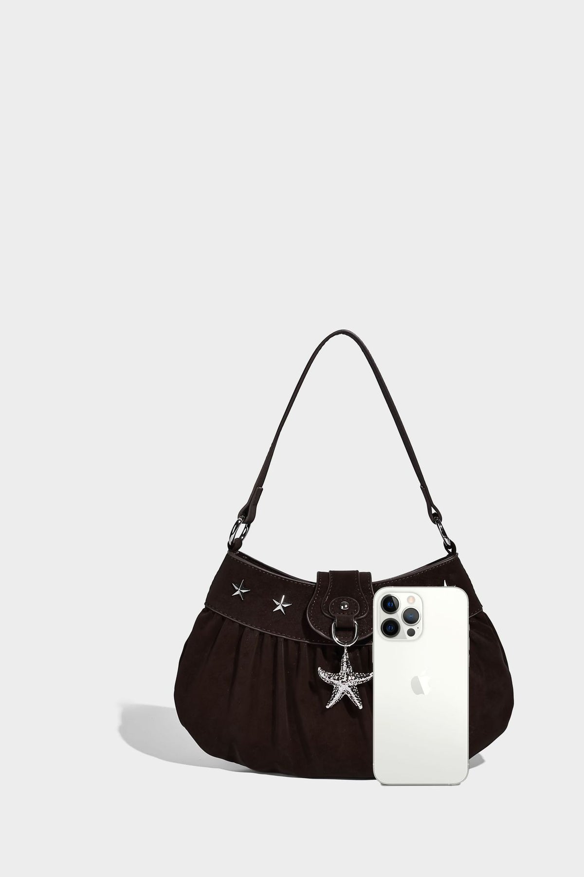 Ruched shoulder bag with curved flap, silver star studs, dangling starfish charm, and adjustable crossbody strap, detail view