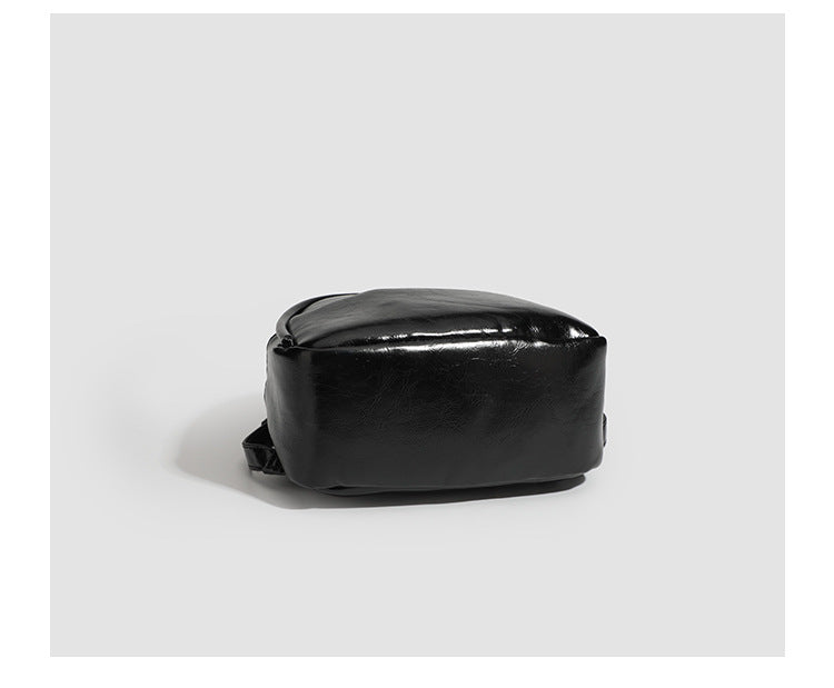 Kompakte, abgerundete Mini-Rucksackhandtasche mit glänzender Lederoptik, Reißverschluss oben, Fronttasche, Tragegriff oben und Detailansicht