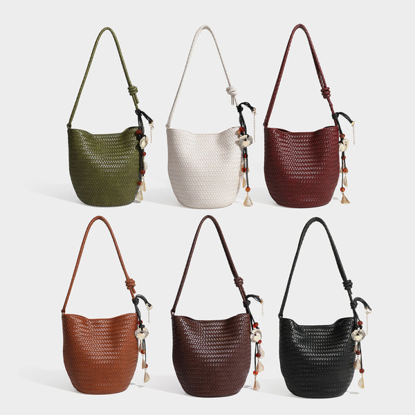 Olive green woven leather-look bucket bag with braided crossbody strap, knotted adjustment, and gold-tone tassel charm with