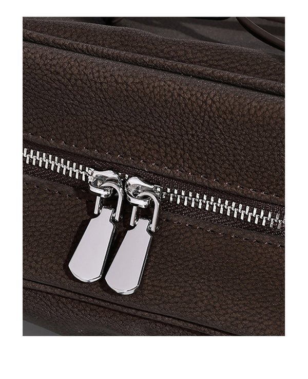 Strukturierte Henkeltasche aus mattem, genarbtem Material mit umlaufendem Riemen und Ringbeschlägen, zwei oberen Tragegriffen und abnehmbarem Crossbody-Riemen