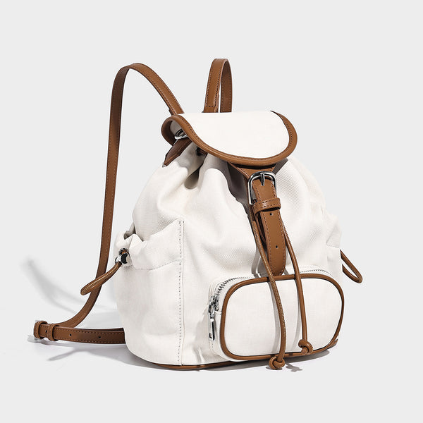 Compact denim drawstring backpack with white leather-look piping, flap-top buckle closure, front zip pocket, and silver-tone
