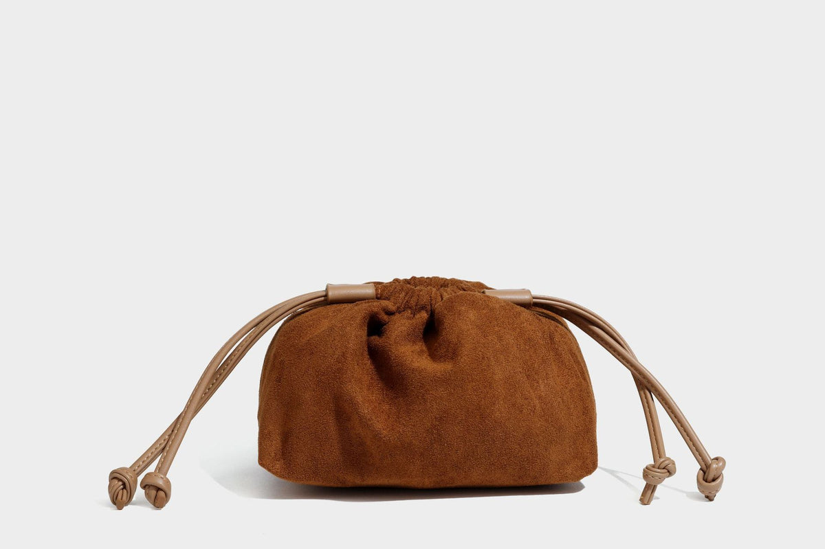 Pebbled leather-look bucket tote bag with rolled double handles, drawstring closure, braided cord charm, and detachable