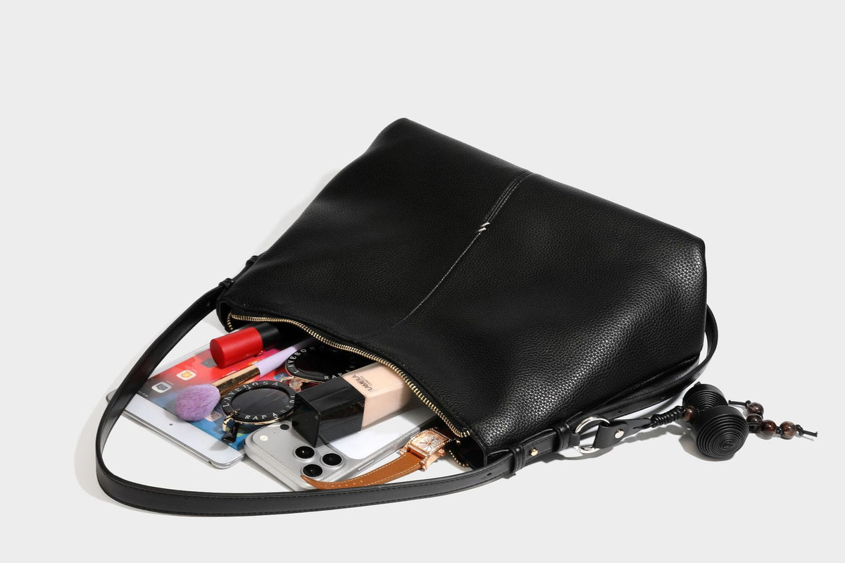 Slouchy hobo shoulder bag with pebbled leather-look finish, zip-top closure, gold-tone hardware, and hanging bead charm