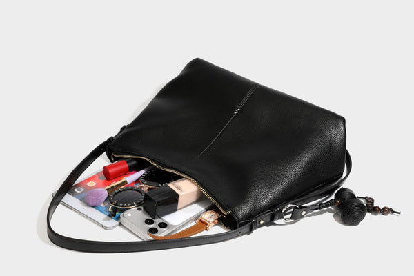 Slouchy hobo shoulder bag with pebbled leather-look finish, zip-top closure, gold-tone hardware, and hanging bead charm
