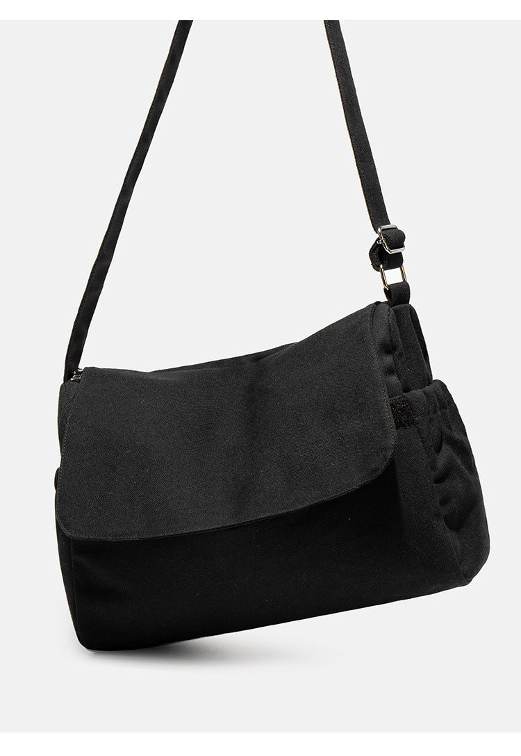 Große schwarze Messenger-Tasche aus mattem Canvas mit Überschlag vorn, Reißverschluss oben, elastischen Seitentaschen und verstellbarem silberfarbenem