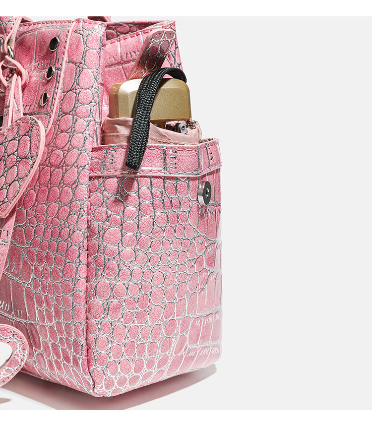 Blush pink glossy crocodile-embossed structured tote bag with studded trim, silver-tone hardware, double top handles, and