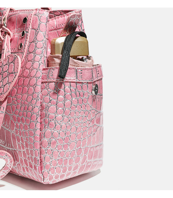 Blush pink glossy crocodile-embossed structured tote bag with studded trim, silver-tone hardware, double top handles, and