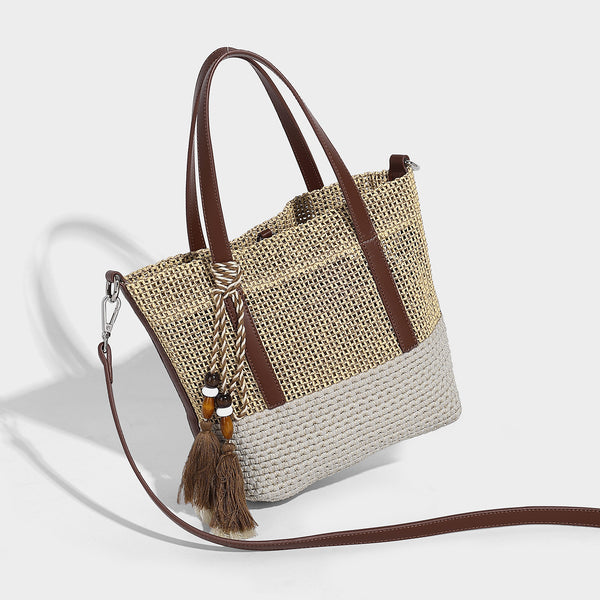 Two-tone open-weave tote bag in beige and cream with brown leather-look handles, tassel bead charm, and detachable