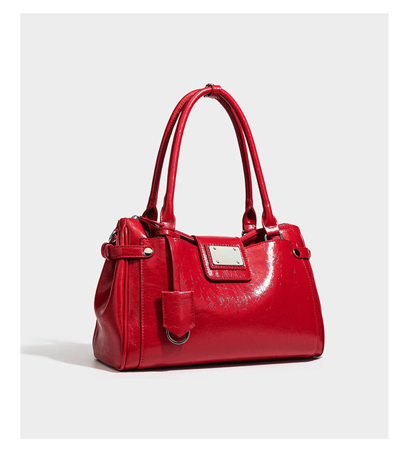 Structured glossy crinkled leather-look satchel with double top handles, front metal-plaque tab, silver-tone hardware, and
