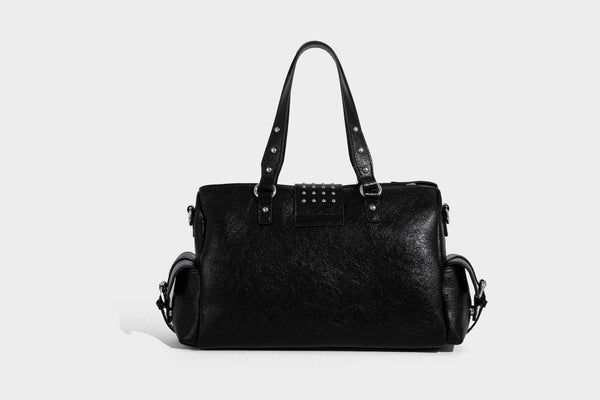 Schwarze, glänzende Henkeltasche mit genarbter Struktur, silberfarbenen Nieten, Riemendetail mit Schnalle, zwei Henkeln und breitem, mit Nieten besetztem Schulterriemen