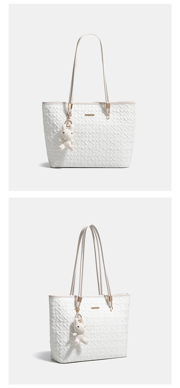 Off-white structured tote bag with dual shoulder straps, gold-tone hardware, and plush bear charm, detail view 9