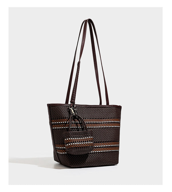 Large structured woven tote bag with striped basket-weave finish, long shoulder straps, and detachable mini pouch charm