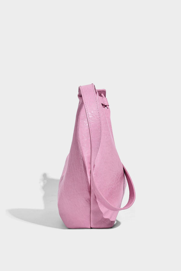 Slouchy crescent half-moon shoulder bag in pink pebbled textured finish with floral charm and knotted side detail, detail