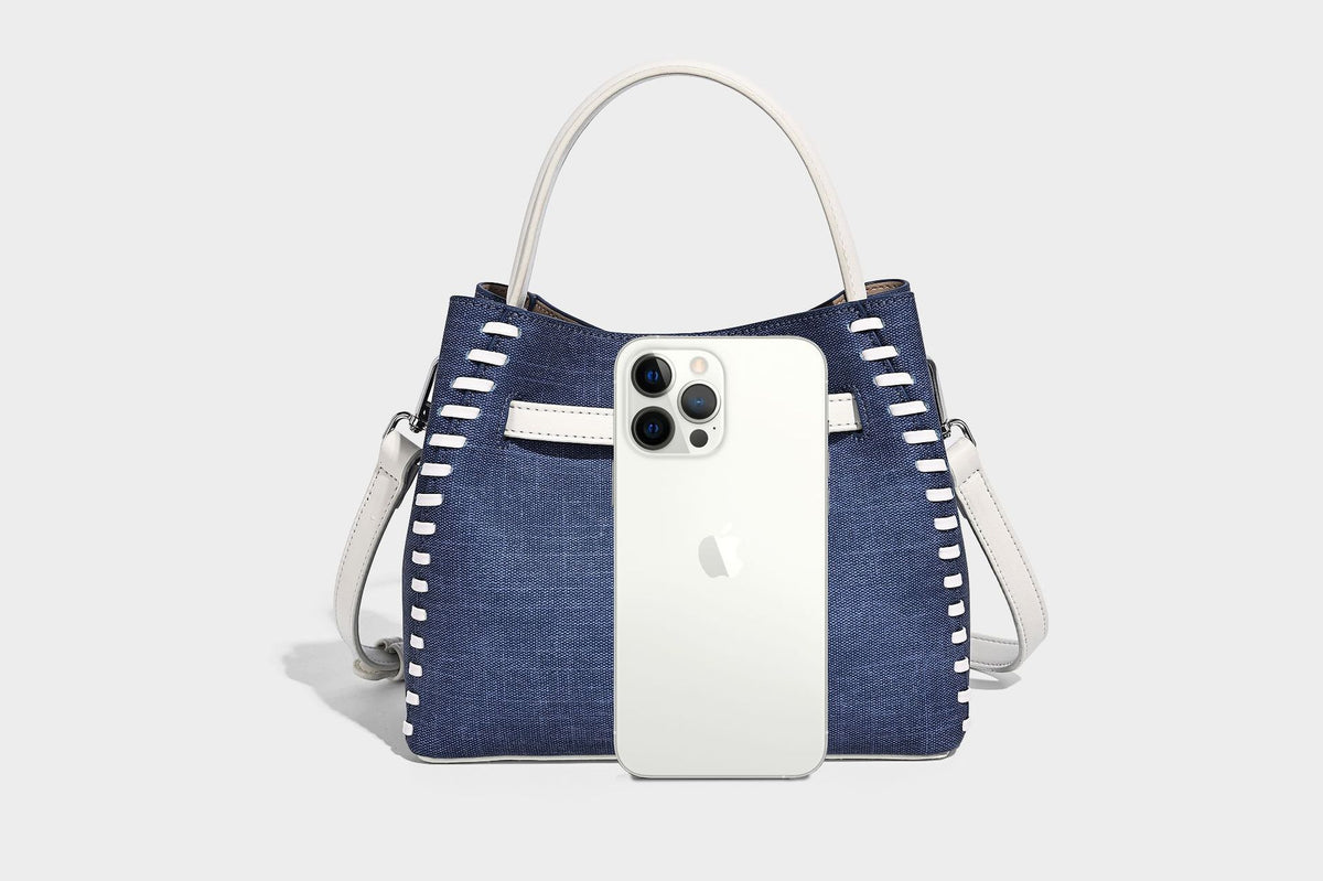 Formstabile Beuteltasche aus Denim mit weißem Zierstich-Besatz, silberfarbenem Drehverschluss, kurzen Henkeln und einem langen verstellbaren