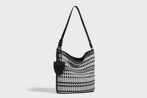 Woven stripe bucket shoulder bag in cream and dark brown with leather-look trim, knotted adjustable strap, and small shield