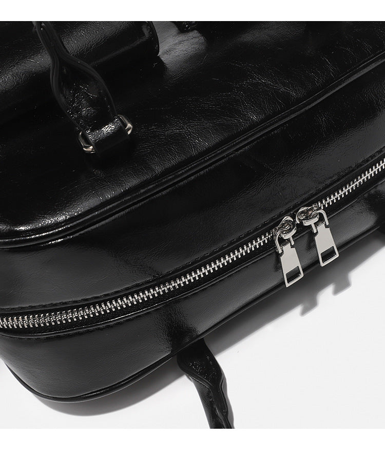 Structured glossy leather-look bowling shoulder bag with two front flap pockets, top zip closure, and long double shoulder