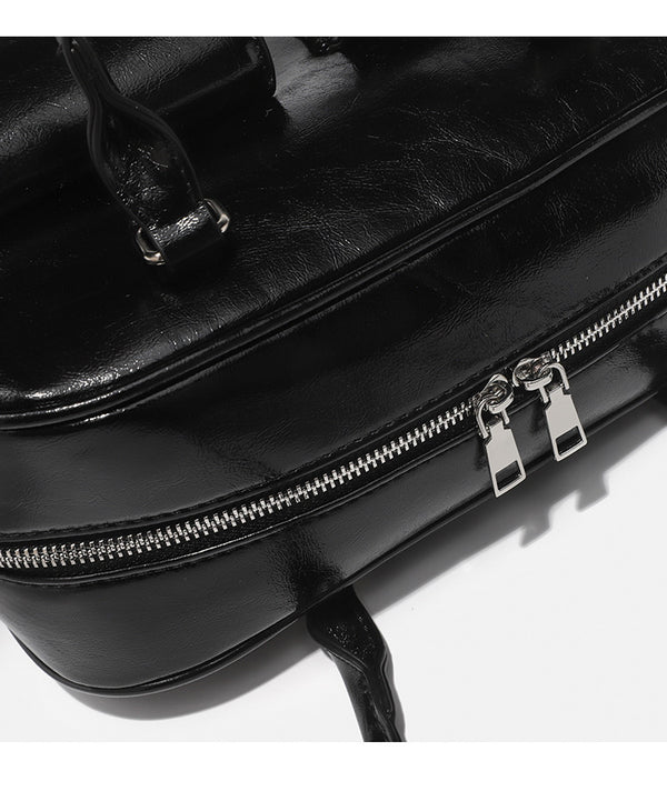 Structured glossy leather-look bowling shoulder bag with two front flap pockets, top zip closure, and long double shoulder