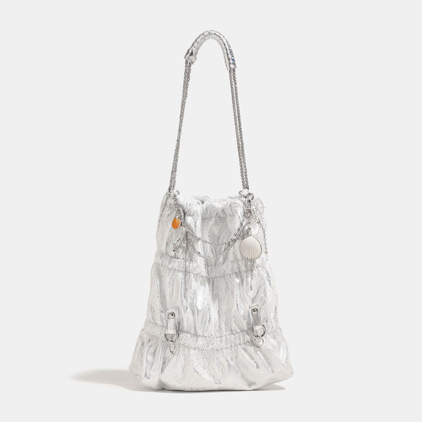Slouchy lace-overlay bucket bag with silver chain strap, draped chain detail, shell charms, and drawstring top closure